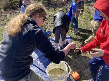 Volunteers help students create grass seed balls.