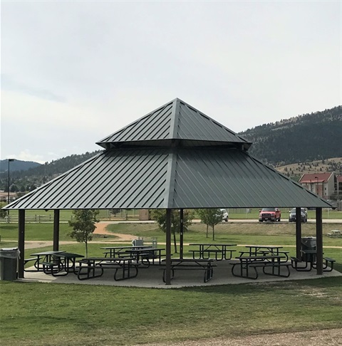 Green shelter with picnic tables in Centennial Park.