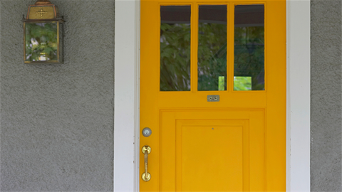 Yellow front door on a grey house.