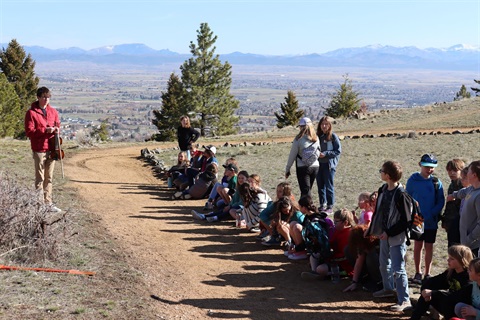 Kids sit next to a trail on Mount Helena overlooking the City.
